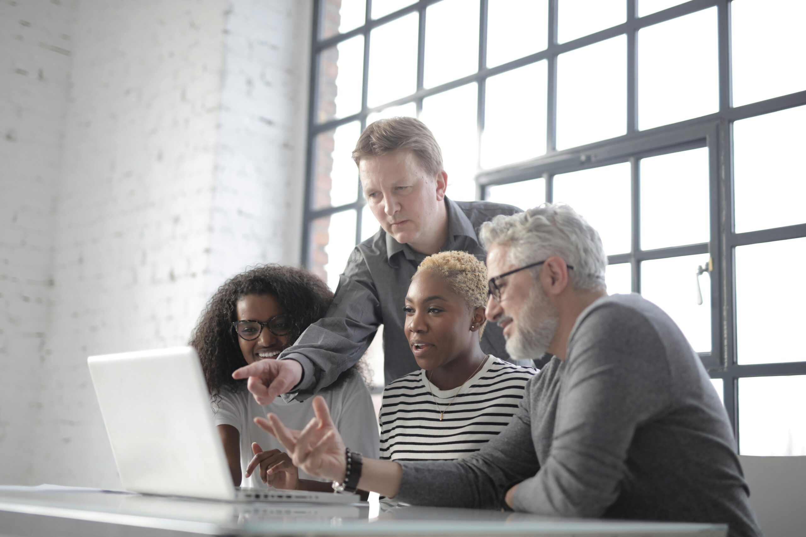 A diverse team all looking at a laptop screen.
